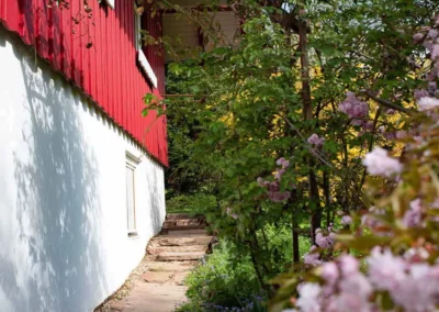 Gartenweg mit Blumen und Rankpflanzen entlang der Fassade des Ferienhauses Brestenberg.