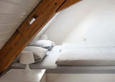 Schlafzimmer mit Doppelbett und sichtbaren Holzbalken im Ferienhaus Brestenberg.