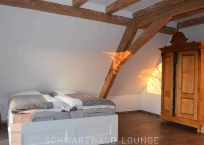 Großes Schlafzimmer unter dem Dach mit sichtbarem Fachwerk und Sonnenlicht im Ferienhaus Brestenberg.
