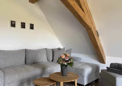 Gemütliche Sitzecke im Schlafzimmer des Ferienhauses Brestenberg mit Sofa, Kunst und Blumen.