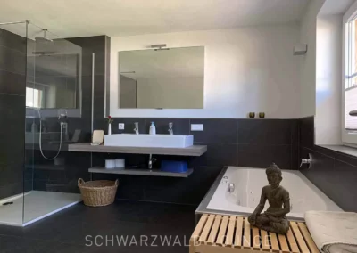 Helles Badezimmer mit Whirlpool, großem Spiegel und moderner Ausstattung im Chalet Schwarzwald Lindenbuch.