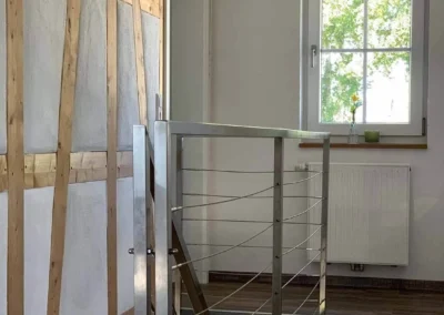 Treppenaufgang mit modernem Metallgeländer und sichtbarem Fachwerk im Chalet Schwarzwald Lindenbuch.