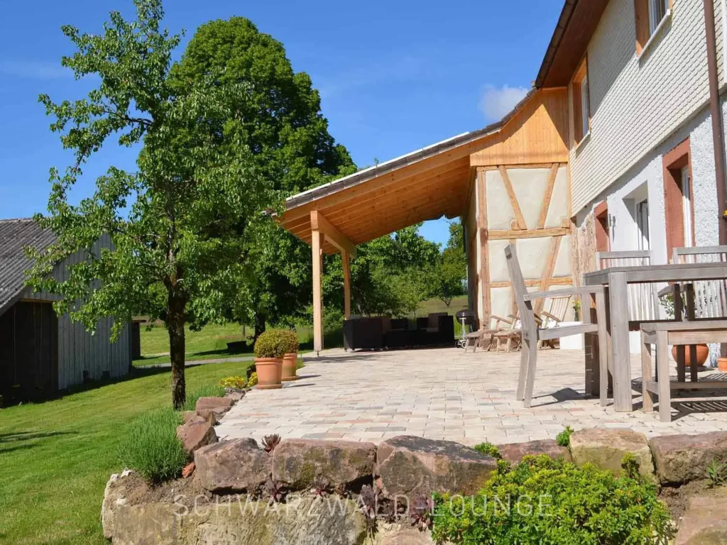 Seitliche Außenansicht vom Chalet Schwarzwald mit großer Sonnenterrasse und naturbelassenem Garten.