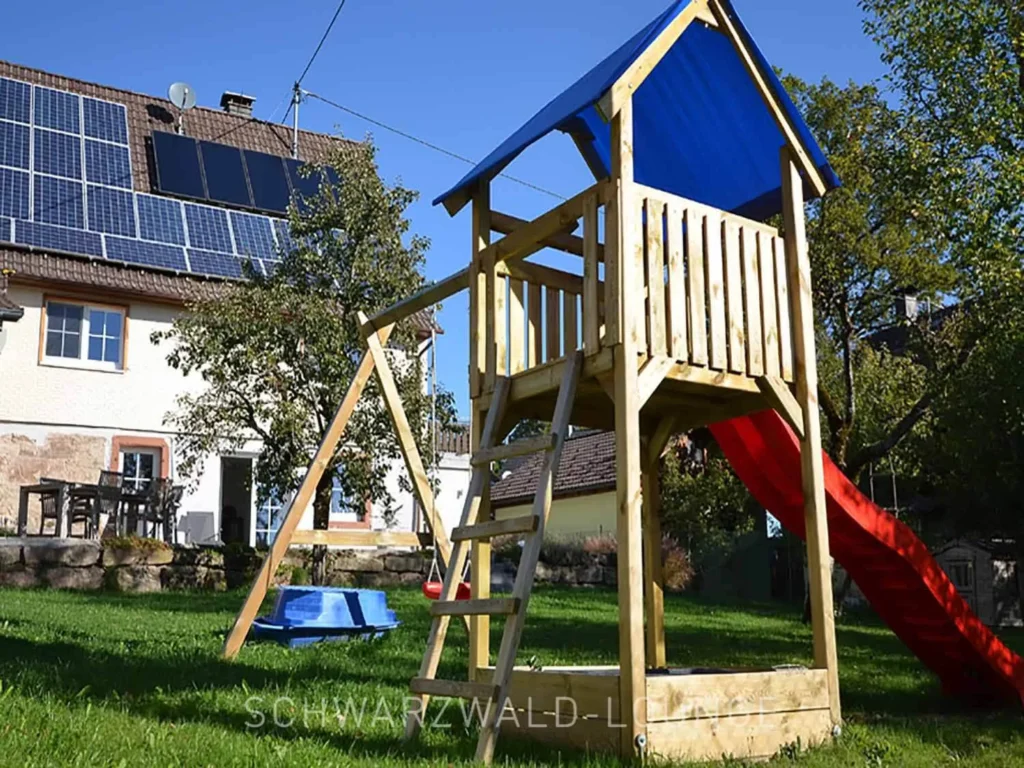 Spielplatz mit Kletterturm und Rutsche im Garten des Chalet Schwarzwald für den perfekten Familienurlaub