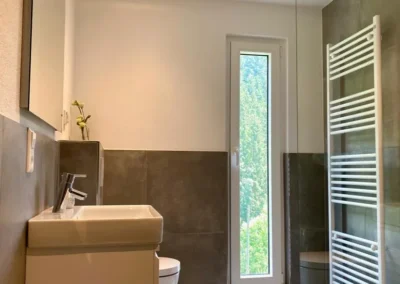 Helles Badezimmer mit großem Fenster, Waschbecken und WC in der Gruppenunterkunft Schwarzwald.