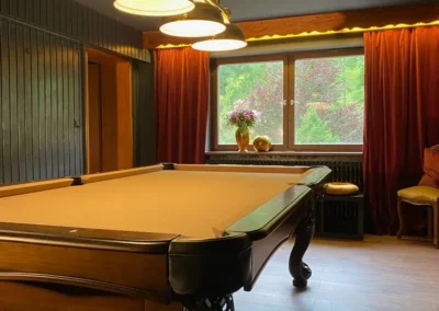Billardzimmer der Gruppenunterkunft Schwarzwald mit großem Billardtisch, klassischen Lampen und Blick ins Grüne.