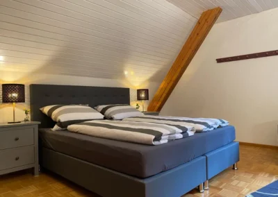 Großzügiges Dachgeschoss-Schlafzimmer mit Boxspringbett und warmem Licht im Ferienhaus Hof Busems.