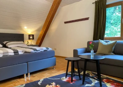 Dachgeschosszimmer mit Doppelbett, Sofa und kleinem Couchtisch im Ferienhaus Hof Busems.