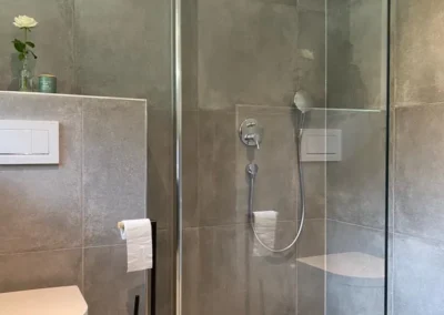 Moderne Dusche mit großem Rainshower-Duschkopf und grauen Fliesen in der Gruppenunterkunft Schwarzwald.