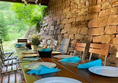Überdachte Terrasse mit langer Esstafel, Holzbank und stimmungsvoller Lichterkette.