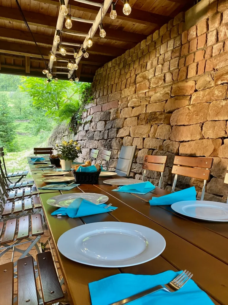 Überdachte Terrasse mit langer Esstafel, Holzbank und stimmungsvoller Lichterkette.
Ferienhaus für große Gruppen
