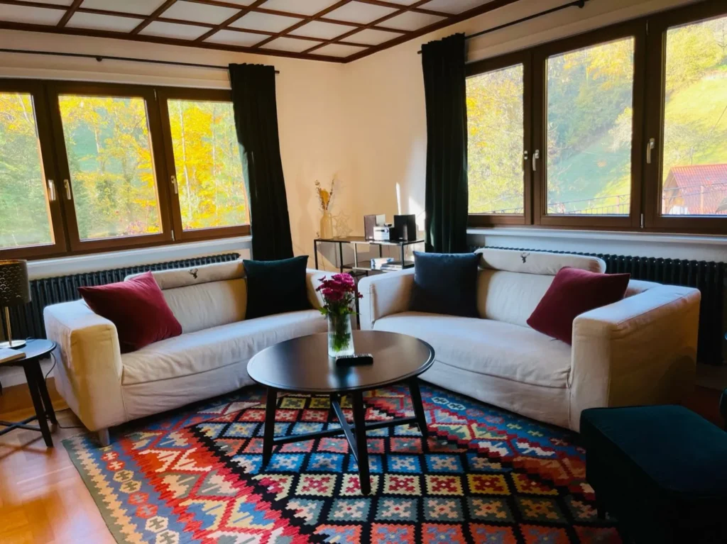 Gemütliches Wohnzimmer der Gruppenunterkunft im Schwarzwald mit zwei Sofas, Panoramafenstern und farbigem Teppich.