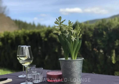 Terrassentisch der Ferienwohnung Kinzigtal mit Blumen, Weingläsern und Blick ins Grüne