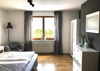 Helles Schlafzimmer der Ferienwohnung Kinzigtal mit Boxspringbett und Blick in den Garten