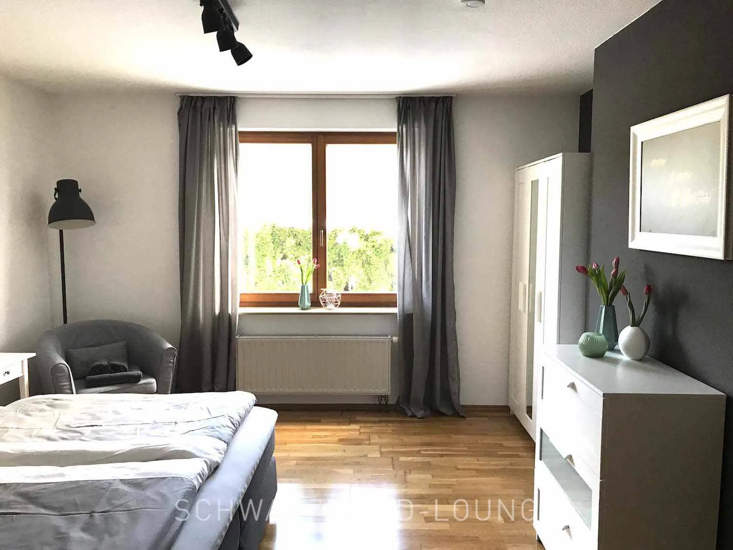 Helles Schlafzimmer der Ferienwohnung Kinzigtal mit Boxspringbett und Blick in den Garten