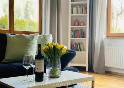 Wohnzimmer der Ferienwohnung Kinzigtal mit Sofa, Weingläsern und frischen Tulpen