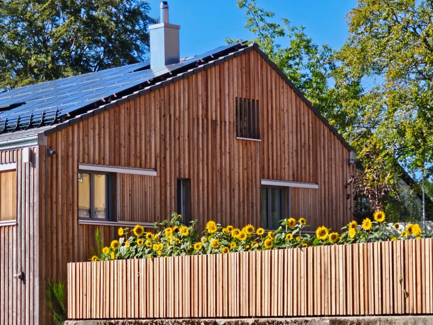 Außenansicht des Holzhauses der Ferienwohnung Ostweg mit Sonnenblumen im Schwarzwald