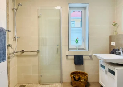 Helles Badezimmer mit großer Dusche, Fenster und Handtuchhaltern in der Ferienwohnung Ostweg im Schwarzwald.