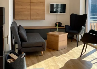 Modernes Wohnzimmer mit Schwedenofen, gemütlichen Sesseln und viel Tageslicht in der Ferienwohnung Ostweg Schwarzwald