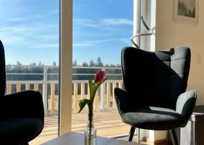 Ostweg Schwarzwald – Wohnzimmer mit zwei Ohrensesseln und Ausblick auf den Schwarzwald in der Ferienwohnung Schwarzwaldlounge