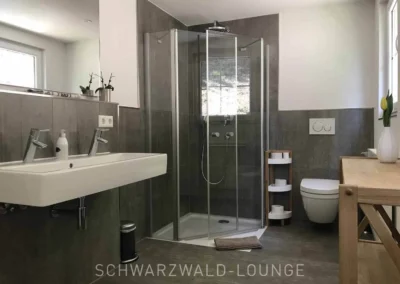 Modernes Badezimmer im Obergeschoss des Schwarzwald Chalet Lohmühle mit großer Dusche und Doppelwaschbecken.