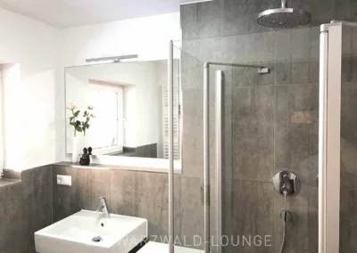 Modernes Bad im Schwarzwald Chalet Lohmühle mit großer Dusche und Wandspiegel.