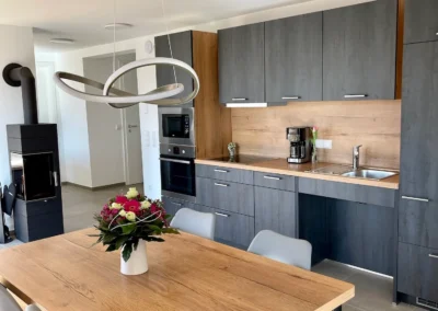 Offene Küche mit Essbereich in der Ferienwohnung Westweg, modernem Design, Kamin und eleganter Hängelampe.