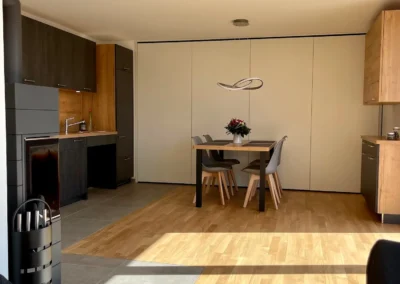 Moderne Küche und Essbereich in der Ferienwohnung Westweg mit Holzakzenten und frischem Blumenstrauß.