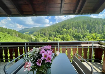 Balkon der Ferienwohnung Bergsee mit Blumenstrauß und weitem Blick ins Schwarzwaldtal.