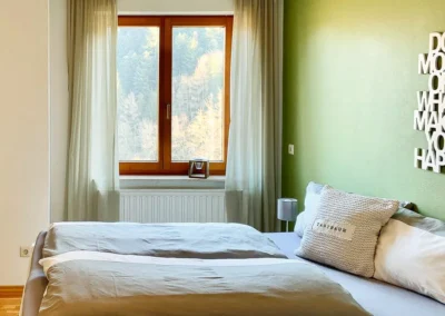 Schlafzimmer mit großem Doppelbett und Fensterblick ins Tal in der Ferienwohnung Bergsee.