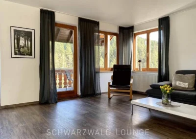 Großes Wohnzimmer mit Sesseln und Panorama-Fenstern in der Ferienwohnung Bergsee Schwarzwald.