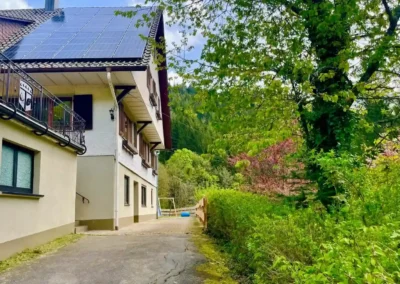 Seitenansicht der Gruppenunterkunft Hof Busems mit Einfahrt, umgeben von dichtem Grün und Schwarzwaldlandschaft.