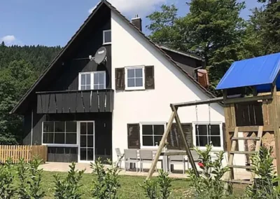 Schwarzwald Chalet Lohmühle – Außenansicht des Ferienhauses mit Garten, Waldkulisse und Spielturm.