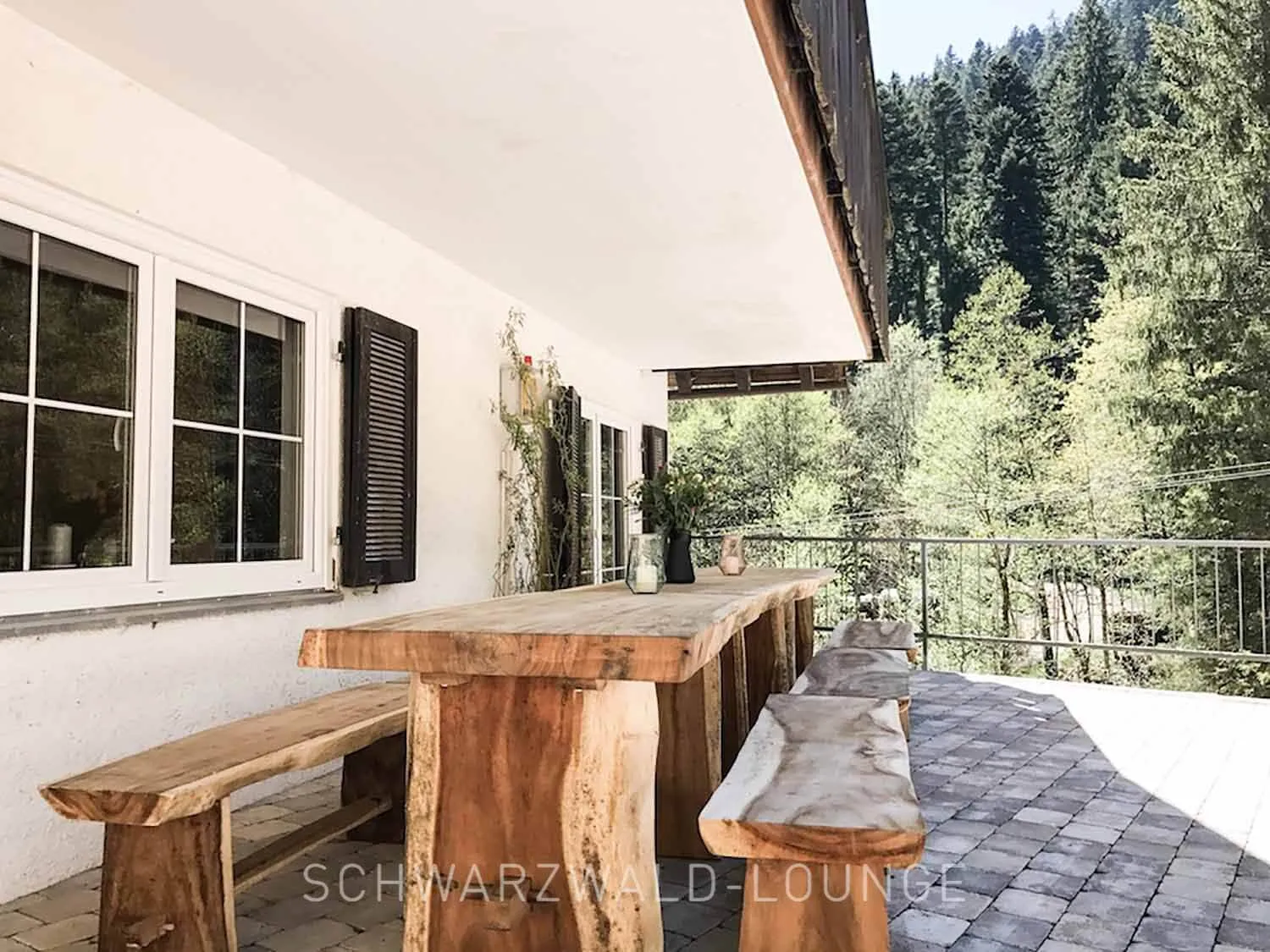 Schwarzwald Chalet Lohmühle – massive Holzbänke und großer Tisch auf der Terrasse am Waldrand.