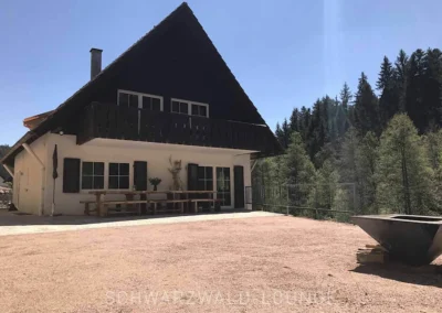 Grillplatz und Außenbereich des Schwarzwald Chalet Lohmühle mit Feuerstelle und großer Holzsitzbank.