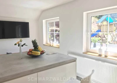 Küche im Schwarzwald Chalet Lohmühle mit Blick auf Fernseher und Garten mit Spielplatz.