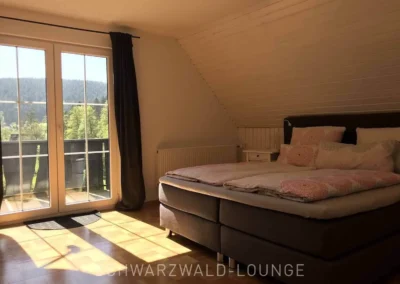 Helles Schlafzimmer im Schwarzwald Chalet Lohmühle mit Boxspringbett und Zugang zum Balkon