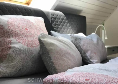 Detailaufnahme der dekorativen Kissen im Schlafzimmer des Schwarzwald Chalet Lohmühle unter dem Dachfenster.