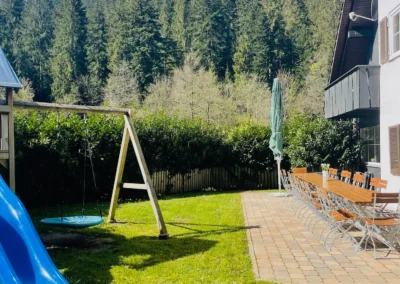 Spielplatz mit blauem Spielturm und Wiese neben der Terrasse des Schwarzwald Chalet Lohmühle.