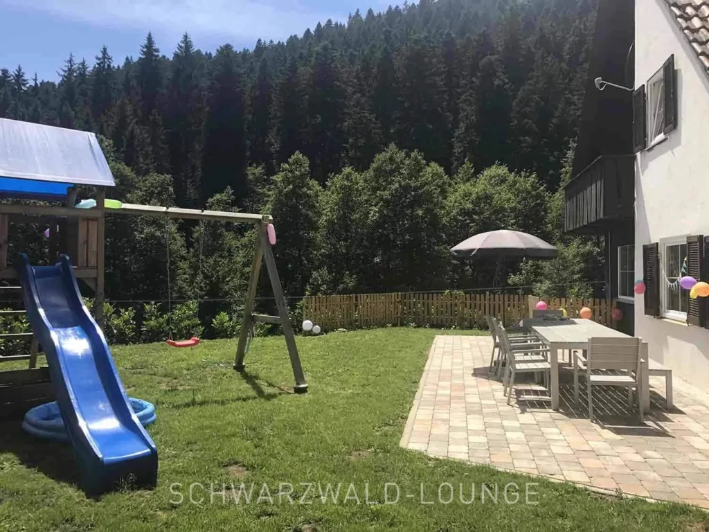 Garten mit Spielplatz, Wiese und dekorierter Terrasse am Schwarzwald Chalet Lohmühle.