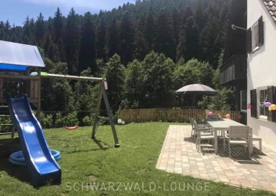 Garten mit Spielplatz, Wiese und dekorierter Terrasse am Schwarzwald Chalet Lohmühle.