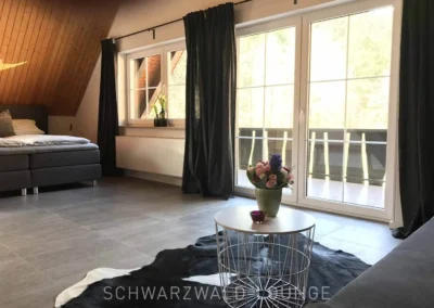 Großes Schlafzimmer mit Boxspringbett und Balkonblick im Schwarzwald Chalet Lohmühle.