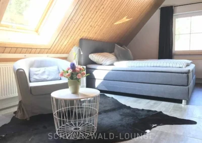 Gemütliche Suite mit Sessel, großem Bett und Dachfenster im Schwarzwald Chalet Lohmühle.