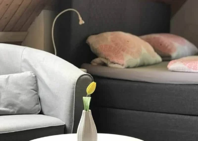 Gemütlicher Sitzbereich mit grauem Sessel und Bett in der Suite des Schwarzwald Chalet Lohmühle.