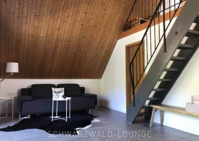 Suite mit Sofa und Treppe zur Galerie im Schwarzwald Chalet Lohmühle.