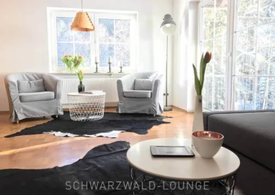 Gemütlicher grauer Sessel mit Dekokissen im unteren Schlafzimmer des Schwarzwald Chalet Lohmühle.