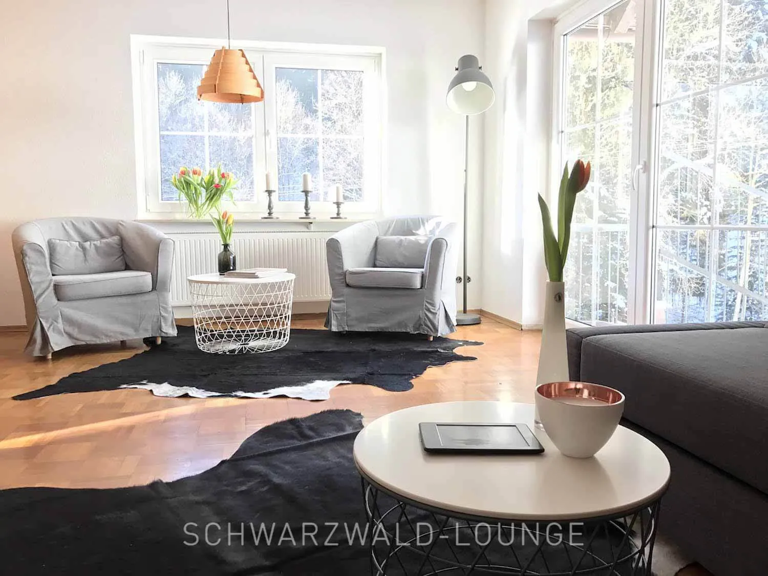 Gemütlicher grauer Sessel mit Dekokissen im unteren Schlafzimmer des Schwarzwald Chalet Lohmühle.