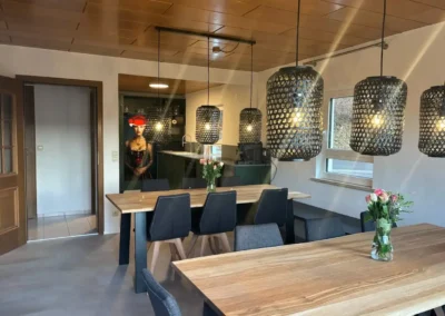 Großzügiger Essbereich mit Holztischen und schwarzen Pendelleuchten im Ferienhaus Tanne und Tal Relax