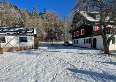 Großes verschneites Grundstück des Ferienhauses Tanne und Tal Relax im Schwarzwald umgeben von Bäumen und Natur.