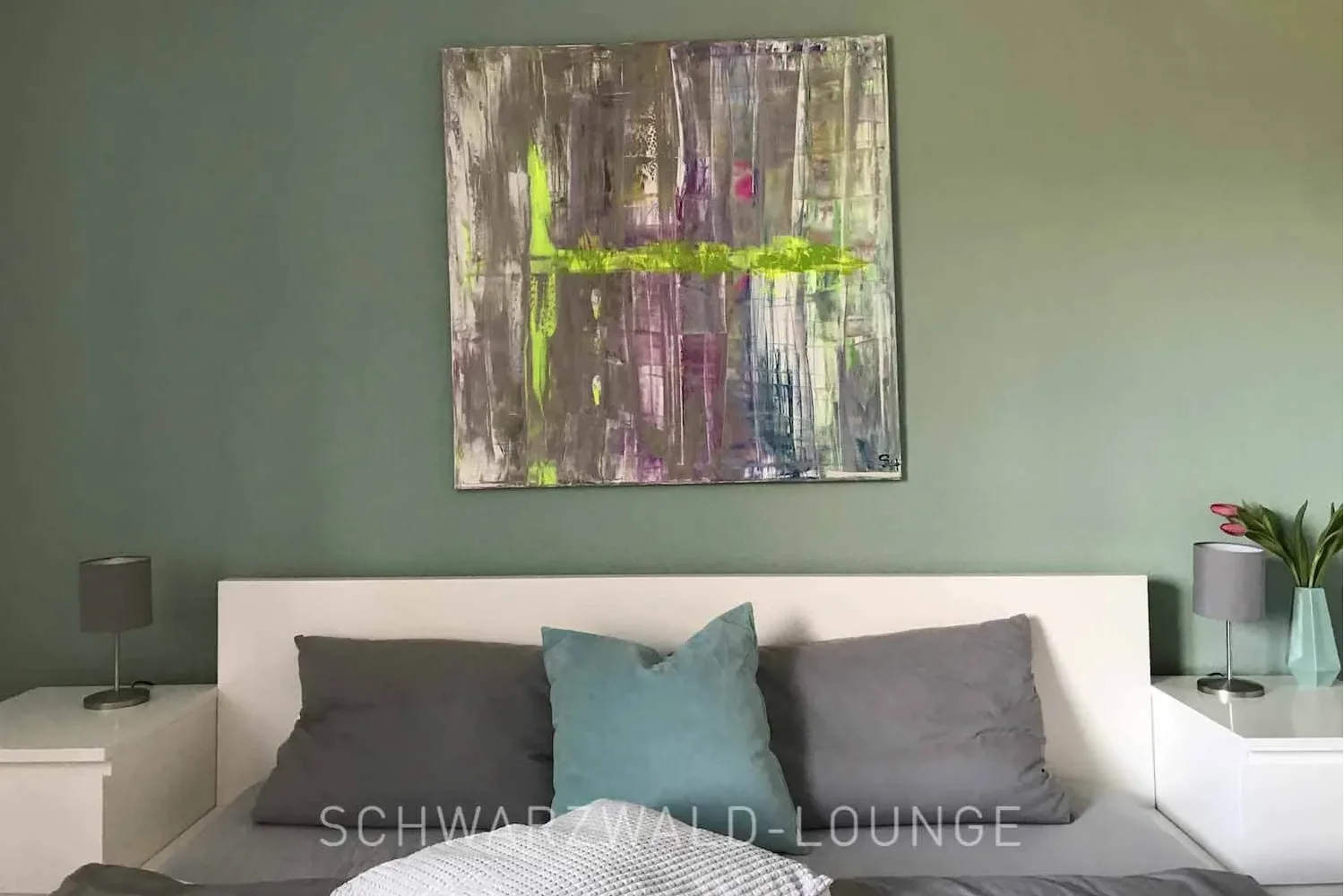 Schlafzimmer der Ferienwohnung Waldwiese mit modernem Doppelbett und Kunstbild im Schwarzwald